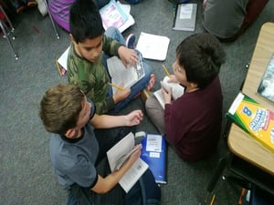 three boys reading and talking about the book